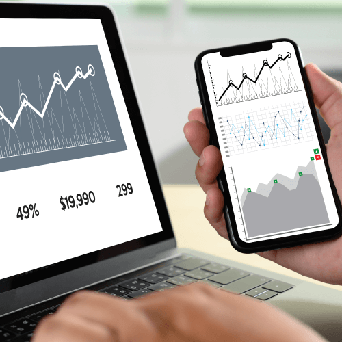 foto de celular e computador com telas mostrando gráficos em crescimento